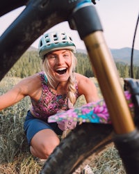 a woman smiling while riding her bike in a field